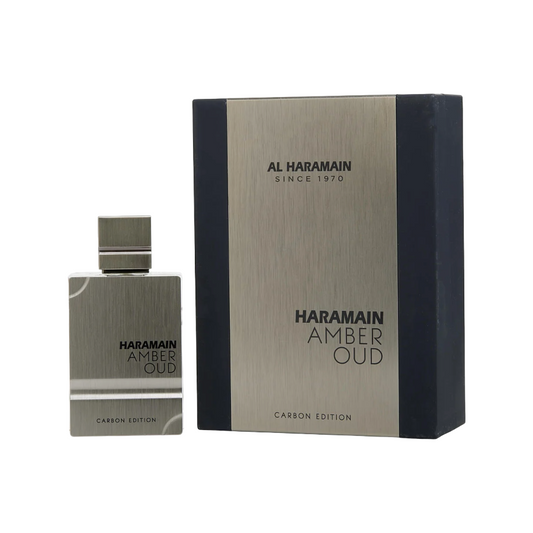 Al Haramain Amber Oud Carbon Edition EDP, showing the perfume bottle and its packaging box. The packaging is mainly black and gold with the brand name and product title visible.