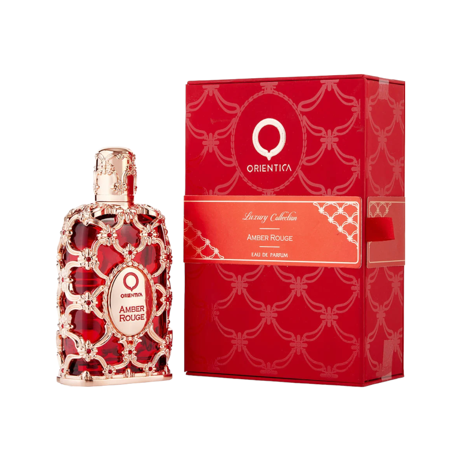 The image shows a red-colored bottle of Orientica Amber Rouge EDP with a gold-tone cap and a decorative pattern on the bottle. The product comes in a matching red box with gold accents and the same decorative design.