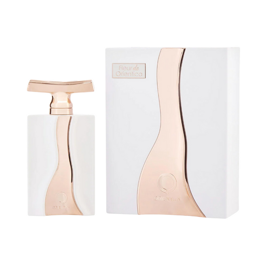 The image shows a bottle of Orientica Fleur De Orientica EDP next to its packaging box. The bottle is white with a copper-colored cap, and the box has a similar color scheme with rose gold accents.