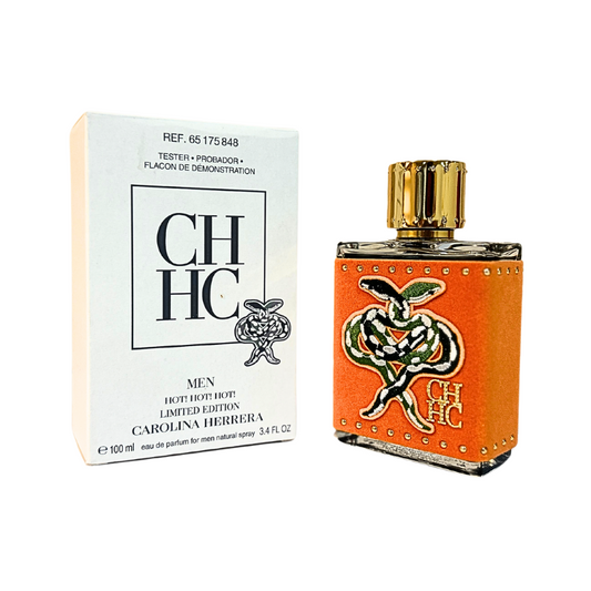 A tester package and a bottle of CH Men Hot! Hot! Hot! cologne by Carolina Herrera. The packaging is primarily white and gold, and the bottle is orange with a gold cap.