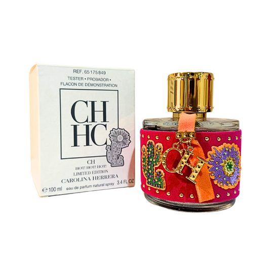 A tester package and a bottle of CH Hot! Hot! Hot! EDP by Carolina Herrera, featuring a colorful decorative band on the bottle.