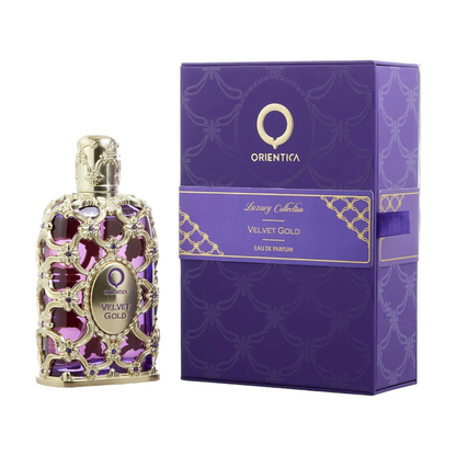 The image shows a bottle of Orientica Velvet Gold EDP with a luxurious design, featuring a purple and gold color scheme, alongside its purple box packaging with gold accents.