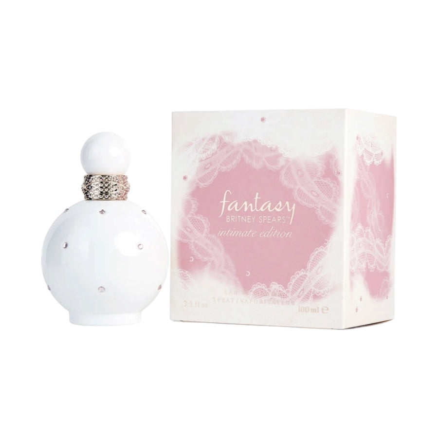 A bottle of Fantasy Britney Spears EDP Intimate Edition perfume with a white cap and a pink label, next to its open box with lace detailing.
