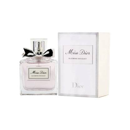 A bottle of Miss Dior Blooming Bouquet eau de toilette for women, accompanied by its packaging box. The bottle is clear, showcasing the light pink fragrance inside, and has a silver cap and bow.