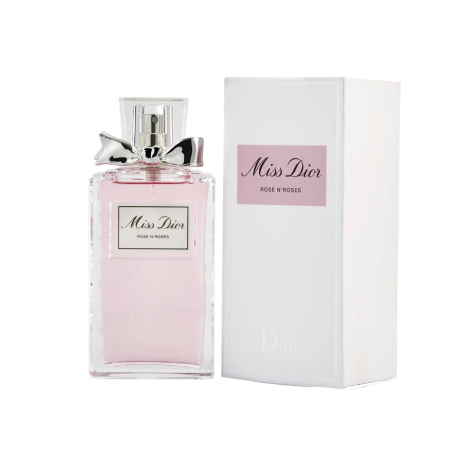 A bottle of Miss Dior Roses N' Roses Eau de Toilette Spray with a pink label, next to its white packaging box with the Christian Dior logo.